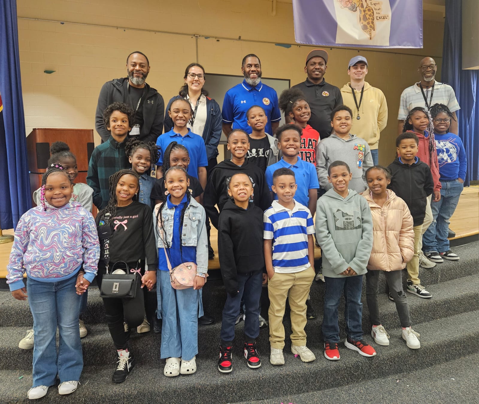 Group of children and community liaisons posing for a photo at a school