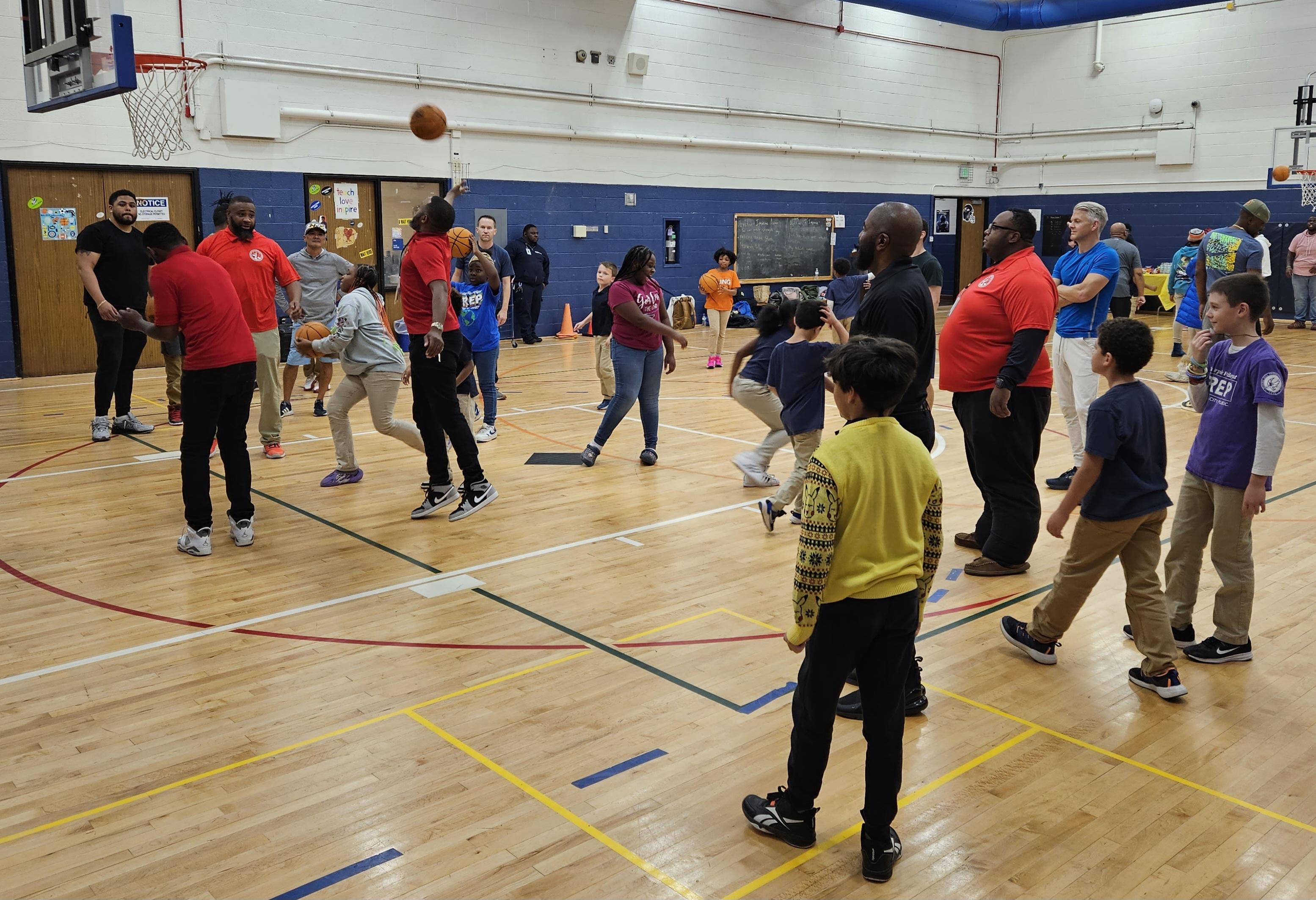 Community liaisons and students play basketball during a school event.